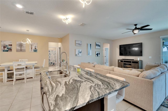 kitchen with visible vents, light stone counters, a sink, and light tile patterned flooring