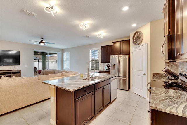 kitchen with stainless steel appliances, open floor plan, a sink, and light tile patterned floors