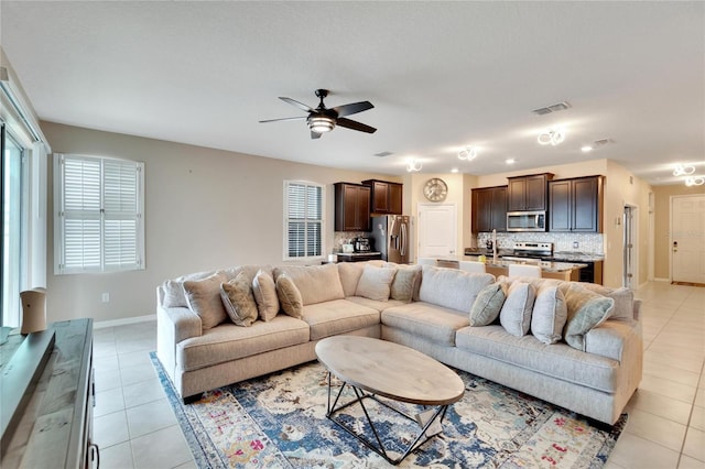 living room with light tile patterned floors, ceiling fan, visible vents, and baseboards