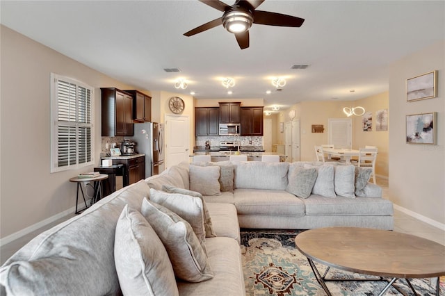 living area with a ceiling fan, light tile patterned flooring, visible vents, and baseboards