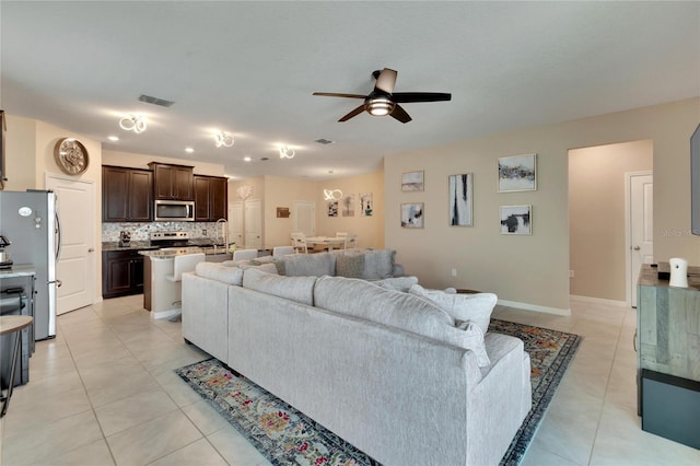 living room featuring light tile patterned floors, ceiling fan, visible vents, and baseboards