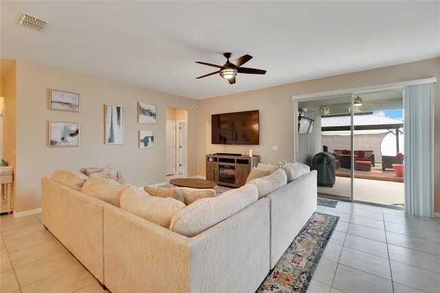 living area featuring arched walkways, light tile patterned flooring, visible vents, baseboards, and a ceiling fan