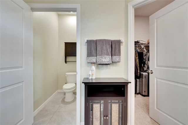 bathroom with toilet, tile patterned flooring, a spacious closet, and baseboards