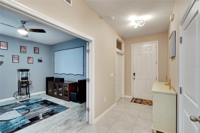 entrance foyer featuring visible vents, light tile patterned flooring, ceiling fan, a textured ceiling, and baseboards