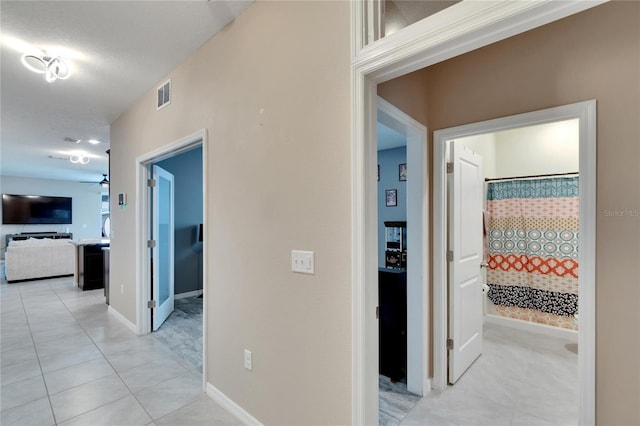 corridor featuring light tile patterned flooring, visible vents, and baseboards