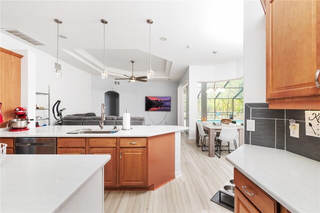 kitchen featuring pendant lighting, sink, stainless steel dishwasher, a tray ceiling, and ceiling fan with notable chandelier