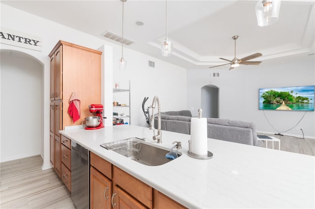 kitchen featuring ceiling fan, sink, a tray ceiling, decorative light fixtures, and light wood-type flooring