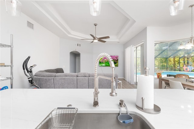 living room with ceiling fan, wood-type flooring, and a raised ceiling