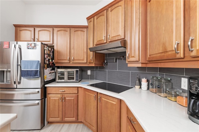 kitchen with tasteful backsplash, stainless steel fridge, black electric stovetop, and light hardwood / wood-style flooring