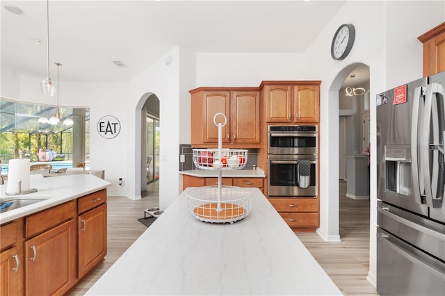 kitchen featuring backsplash, light hardwood / wood-style floors, stainless steel appliances, and pendant lighting