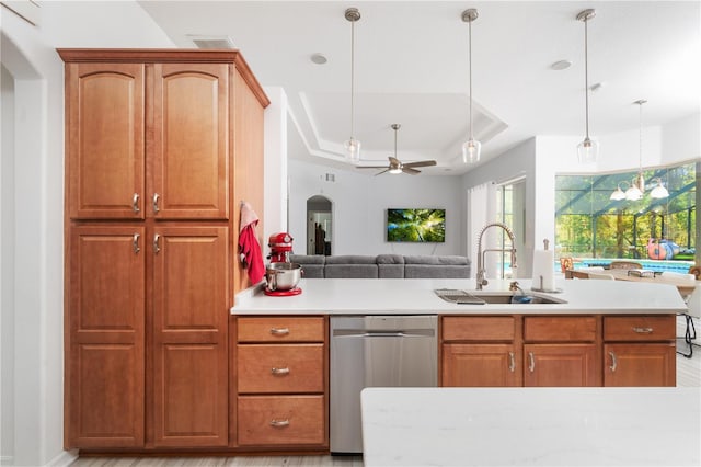 kitchen with sink, ceiling fan, hanging light fixtures, stainless steel dishwasher, and a tray ceiling