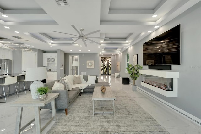 living room featuring ceiling fan, light tile floors, and a tray ceiling