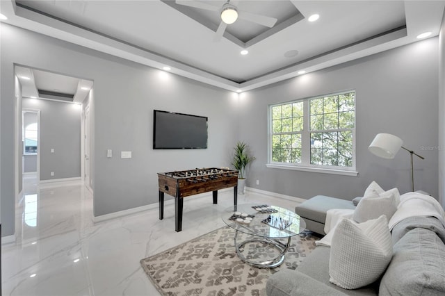 tiled living room with ceiling fan and a tray ceiling