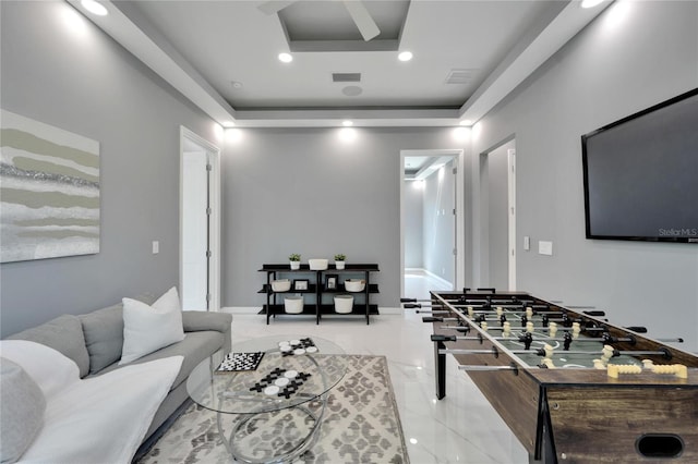 game room with a raised ceiling and light tile floors