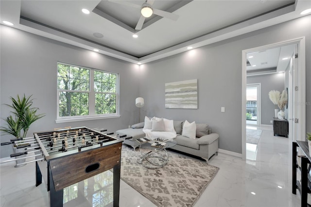 living room featuring a raised ceiling, ceiling fan, and light tile floors