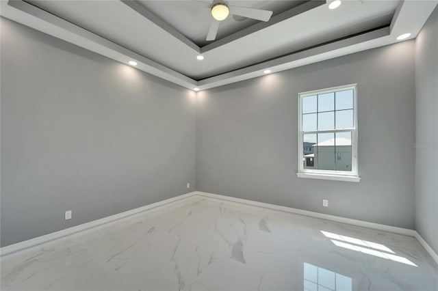 tiled empty room with a raised ceiling and ceiling fan