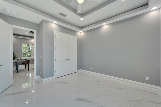 tiled spare room with ceiling fan and a raised ceiling