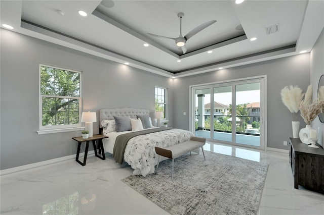 bedroom featuring access to exterior, a tray ceiling, light tile floors, and multiple windows