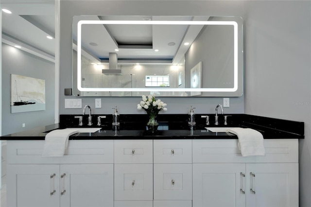 bathroom with a raised ceiling and double sink vanity