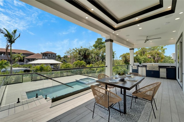 wooden terrace featuring exterior kitchen, a grill, ceiling fan, and a fenced in pool