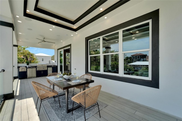 exterior space with light hardwood / wood-style floors, ceiling fan, and a tray ceiling