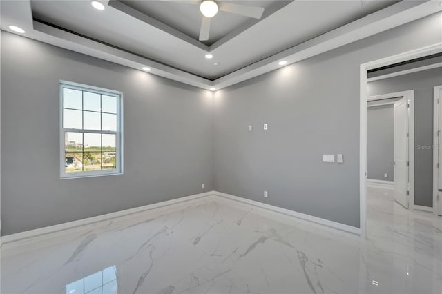 tiled spare room featuring ceiling fan and a raised ceiling