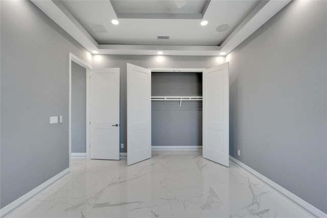 unfurnished bedroom with a closet, a raised ceiling, and light tile floors