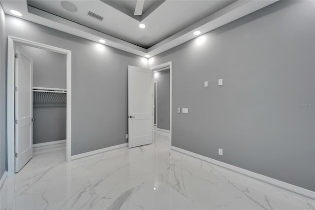 tiled bedroom featuring a closet, a walk in closet, and a raised ceiling