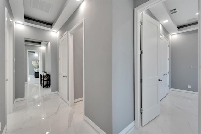 corridor with light tile floors and a raised ceiling