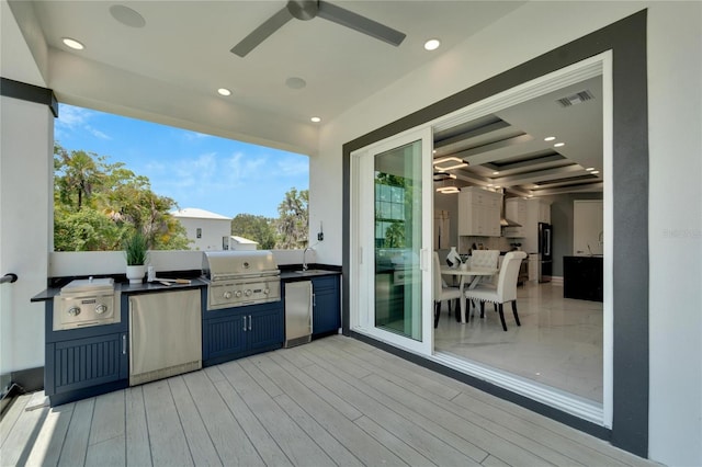 wooden terrace with area for grilling, ceiling fan, and grilling area