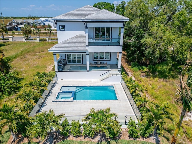 rear view of property featuring a patio, a yard, and a swimming pool with hot tub