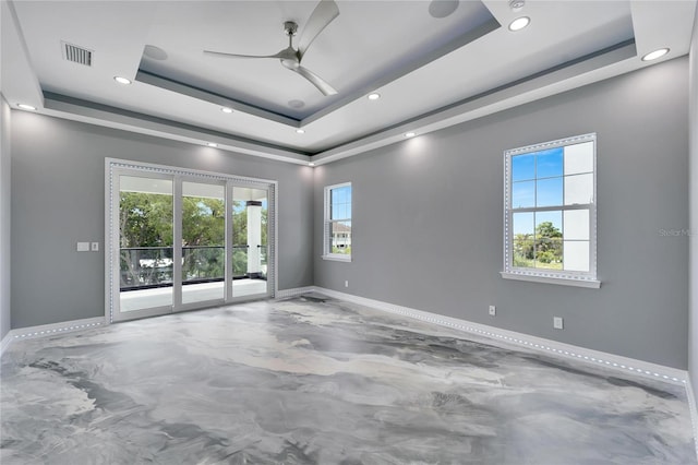 empty room featuring ceiling fan and a tray ceiling