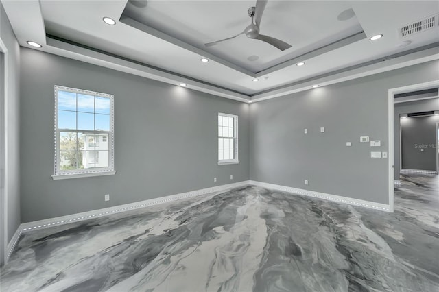 empty room with ceiling fan, a tray ceiling, and a healthy amount of sunlight