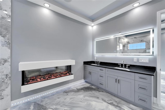 bathroom with dual sinks, oversized vanity, concrete floors, and a multi sided fireplace