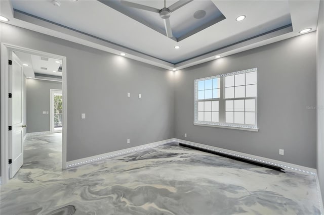 empty room with ceiling fan, a raised ceiling, and a healthy amount of sunlight