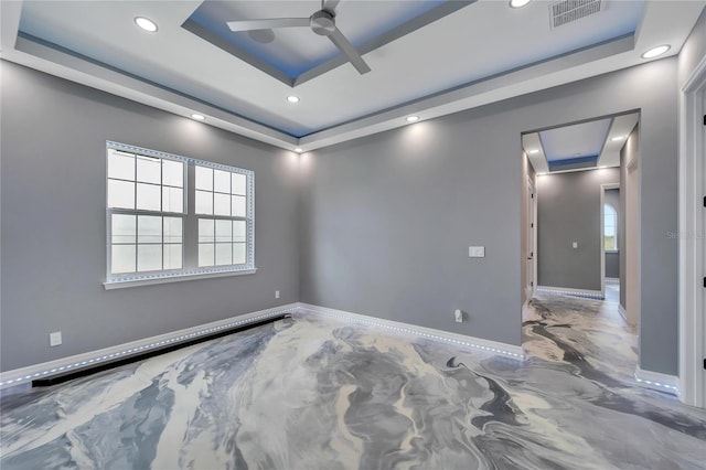 empty room with ceiling fan, plenty of natural light, and a tray ceiling