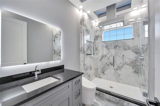 bathroom featuring toilet, vanity, and a shower with door