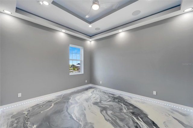 unfurnished room with ceiling fan and a tray ceiling