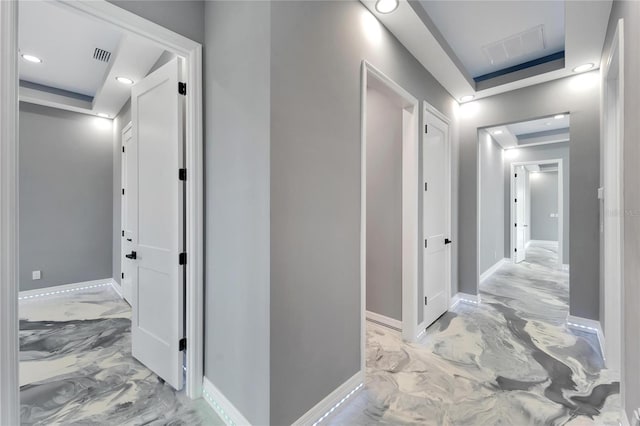 hallway featuring light tile floors and a tray ceiling