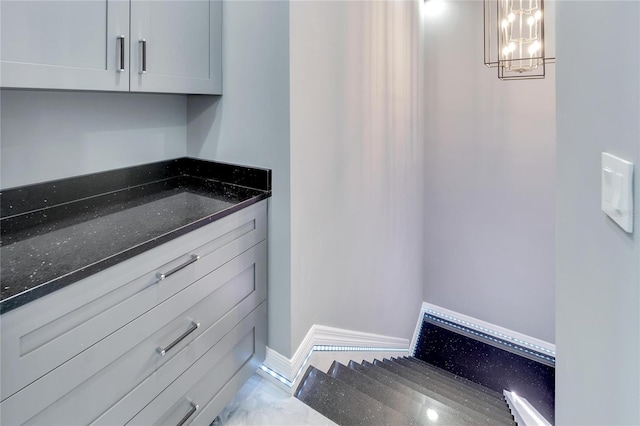 interior space with dark stone counters, a chandelier, and light tile floors