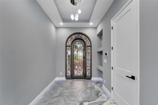 foyer featuring a raised ceiling and an inviting chandelier