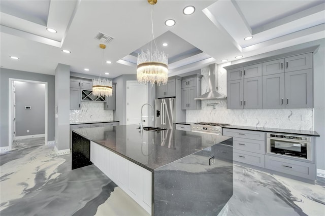 kitchen featuring a raised ceiling, tasteful backsplash, wall chimney exhaust hood, and decorative light fixtures