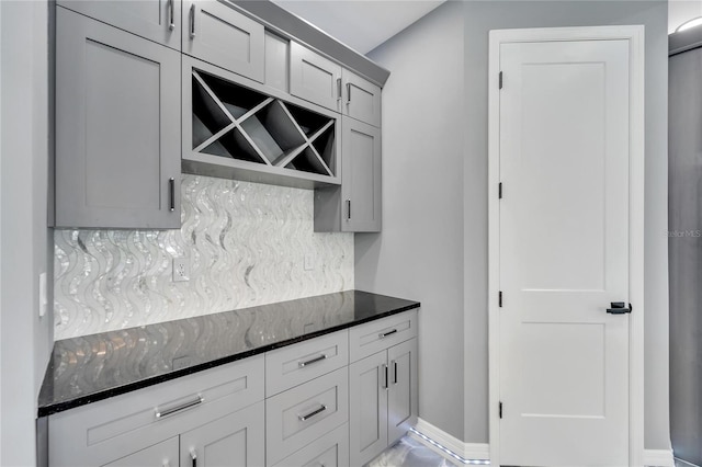 kitchen featuring dark stone counters, backsplash, and gray cabinets