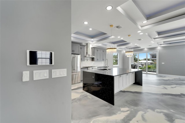 kitchen with pendant lighting, tasteful backsplash, stainless steel fridge, a center island with sink, and wall chimney exhaust hood