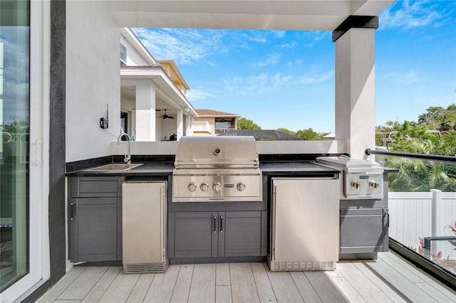 wooden terrace featuring ceiling fan, grilling area, sink, and an outdoor kitchen