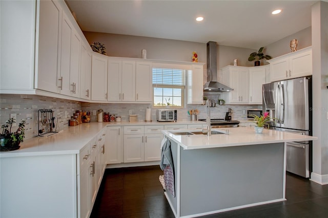 kitchen with a center island with sink, white cabinetry, tasteful backsplash, and wall chimney range hood