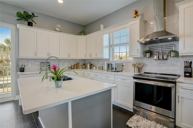 kitchen with stainless steel range with electric cooktop, white cabinetry, tasteful backsplash, and wall chimney range hood