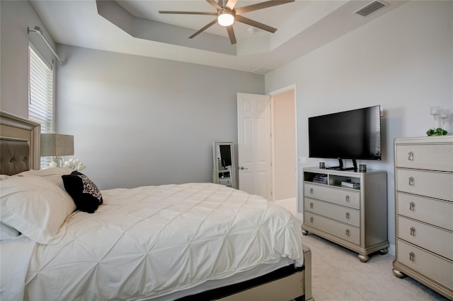 carpeted bedroom featuring ceiling fan and a tray ceiling