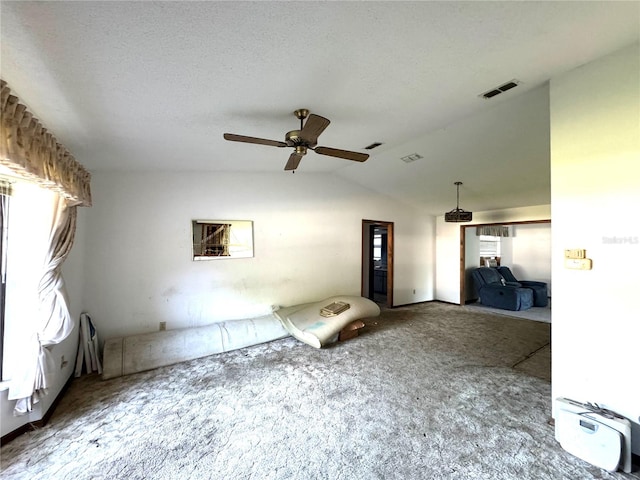 unfurnished living room featuring dark carpet, vaulted ceiling, ceiling fan, and a textured ceiling