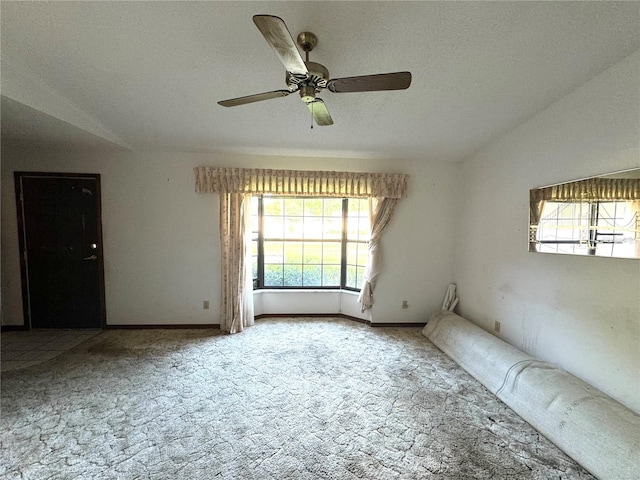 carpeted empty room featuring lofted ceiling, ceiling fan, and a textured ceiling